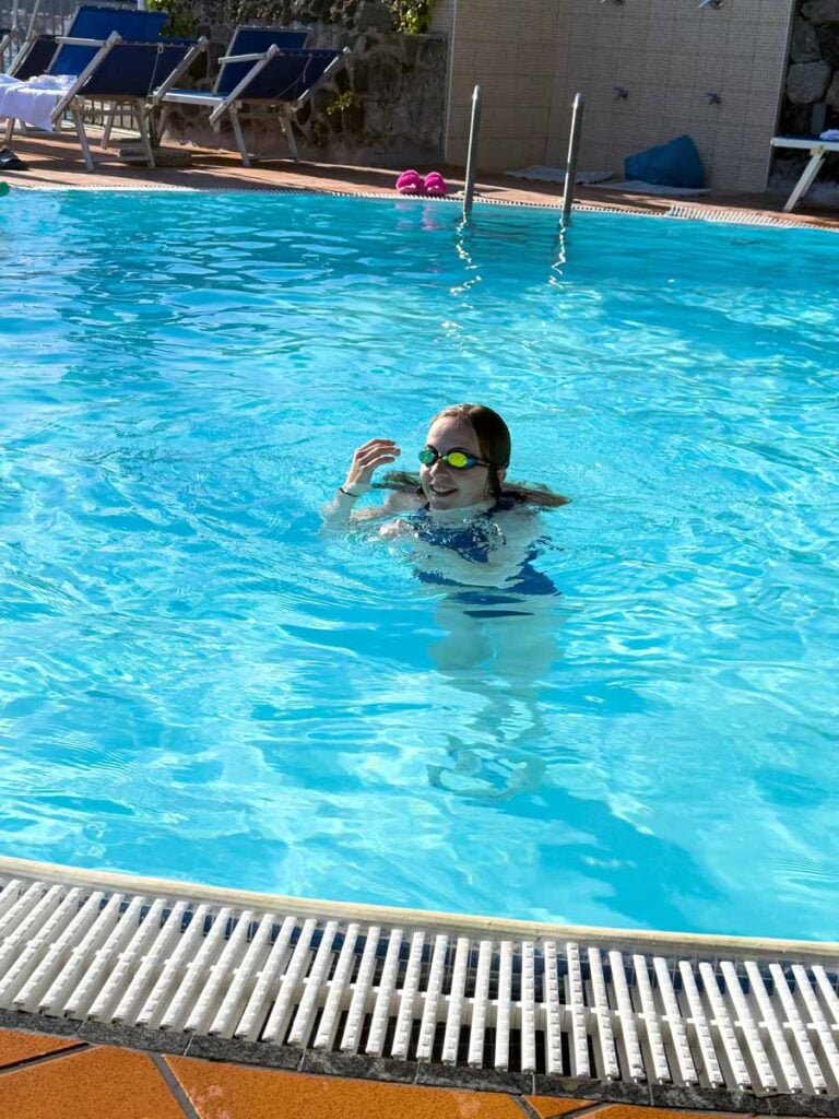 a 12-year old girl swims in the thermally heated rooftop pool at Aragona Palace Hotel & Spa in Ischia, Italy.