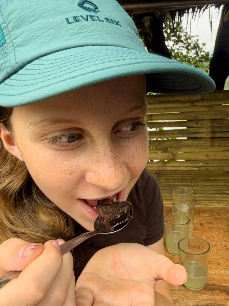 A Brewer child tries freshly made brown sugar at the Friday market near Bukit Lawang.