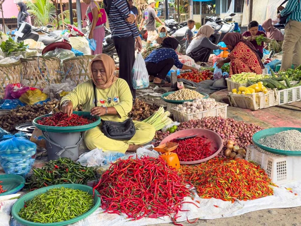 A vendor at the Bukit Lawang Friday market sells colorful chili peppers.