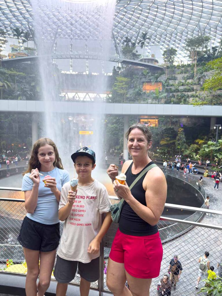 Celine Brewer, from the Family Can Travel blog, stands in front of the Rain Vortex at the Jewel at the Singapore Airport.