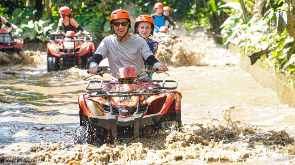 Dan Brewer, owner of FamilyCanTravel.com, and his daughter ride their ATV through deep water during a family trip to Bali, Indonesia.