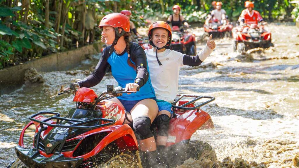 Celine Brewer and her son drive an ATV through deep, muddy water on an adventure tour in Bali.