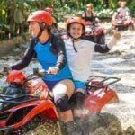 Family Trip to Bali - kid-friendly ATV Tour Celine Brewer and her son drive an ATV through deep, muddy water on an adventure tour in Bali.