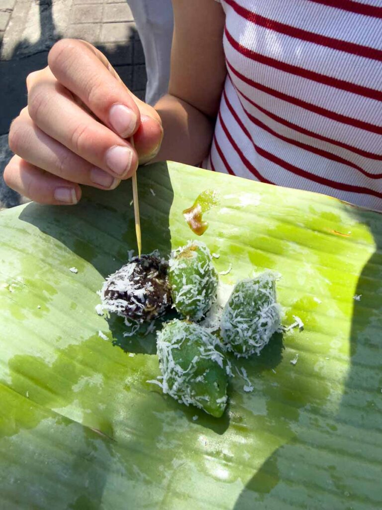 A Brewer child tries sugar bombs at Tanah Lot during a family-friendly sightseeing tour in Bali.