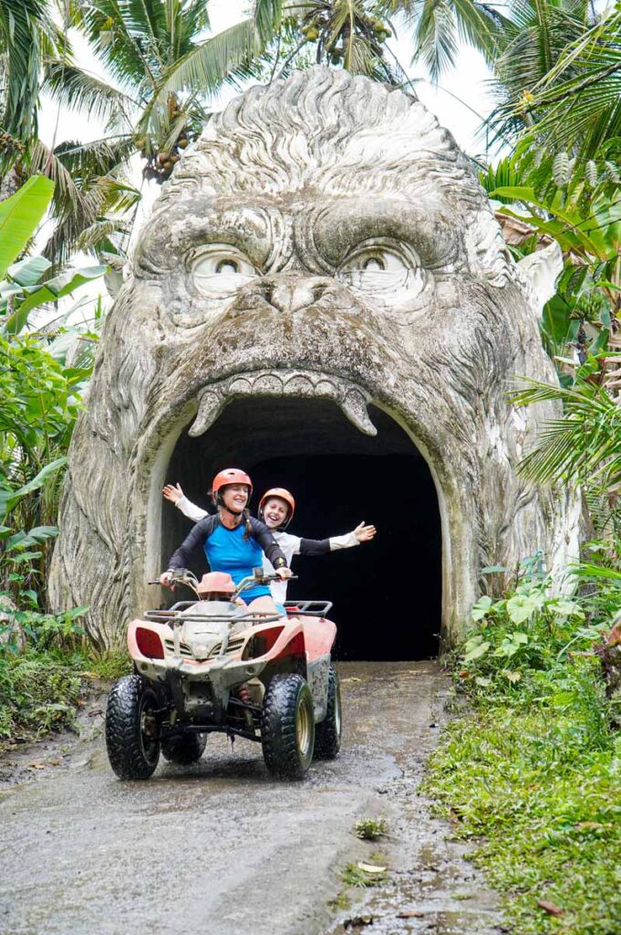 Celine Brewer, owner of the Family Can Travel blog, and her son drive an ATV through a gorilla face tunnel on a kid-friendly ATV tour in Bali.