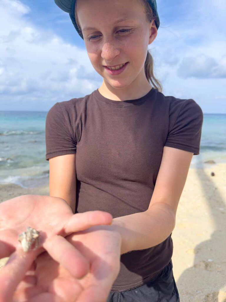 A Brewer child, from FamilyCanTravel.com, holds a hermit crab on the beach during a family trip to Pulau Weh, Indonesia.