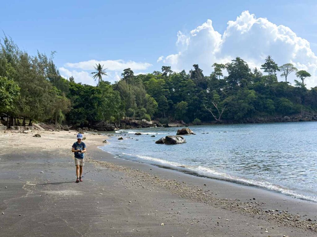 A Brewer child walks on a black sand beach during a tuk tuk tour of Pulau Weh, Indonesia.