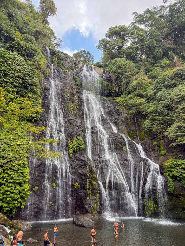 Swimmers stand in a pool beneath the Banyumala Twin Waterfalls in Bali, Indonesia.