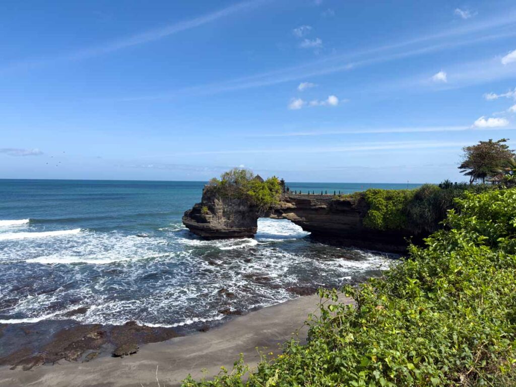 Pura Batu Bolong on a peninsula with a rock arch near Tanah Lot, Bali.